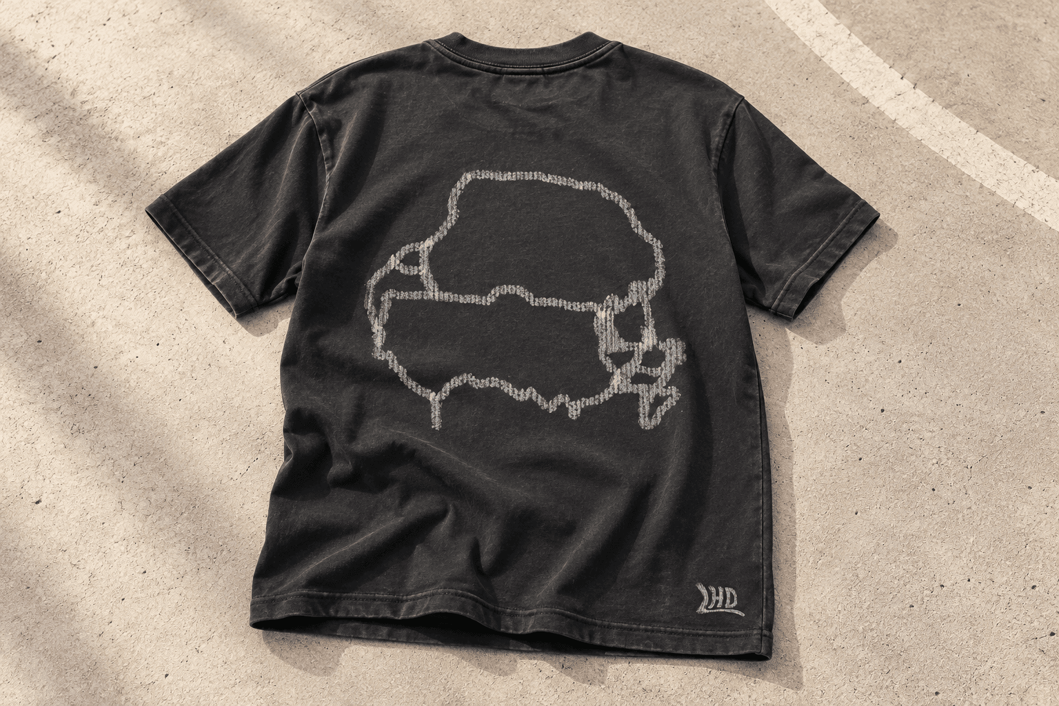 LHD charcoal tee laid on pale concrete, showing the route graphic, sleeves and hem without a model